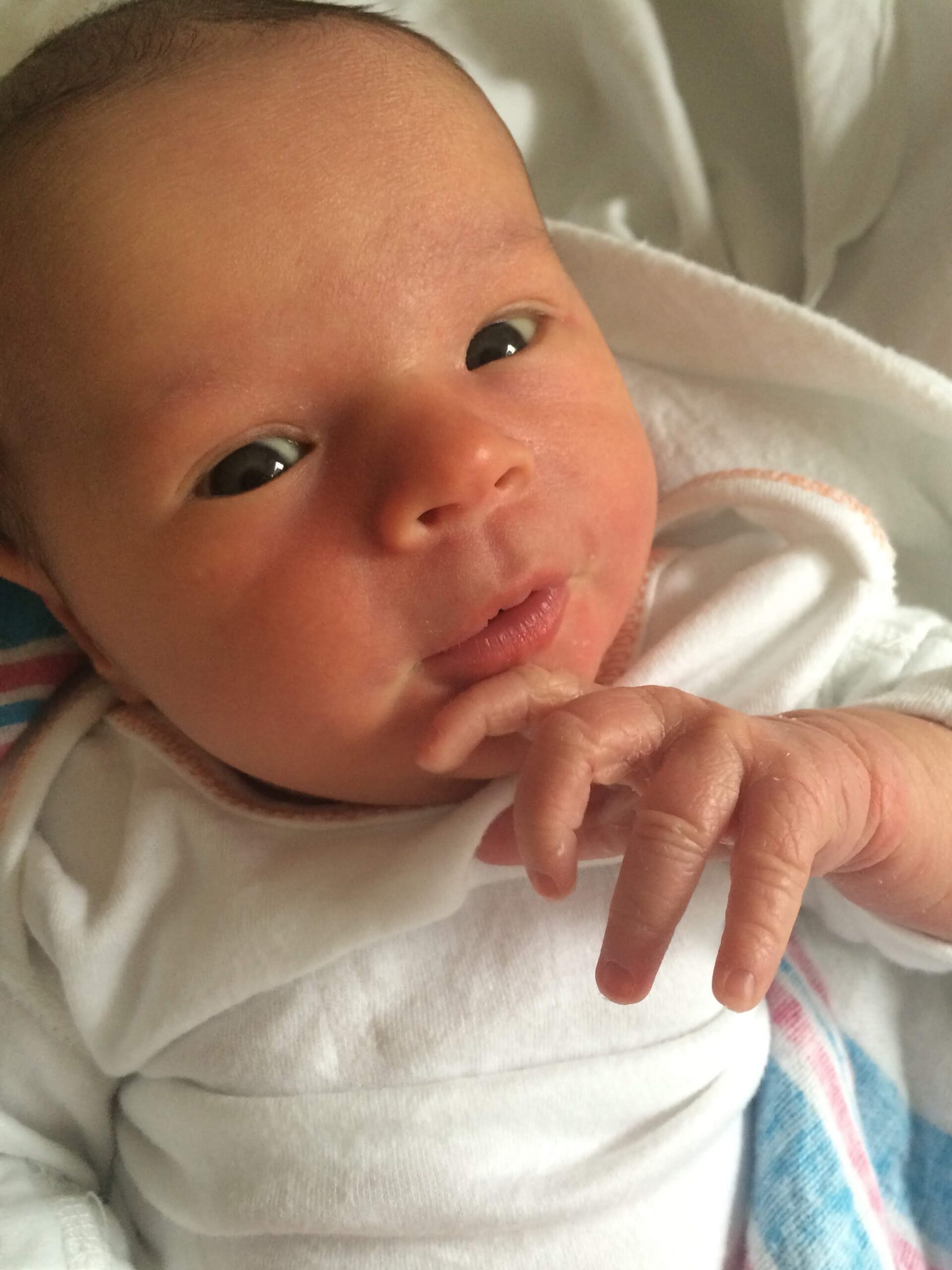 Newborn baby looking wide-eyed and alert, showing early signs of awareness.